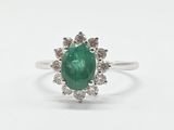 gros plan d'une bague avec une pierre verte entourée de diamants blancs