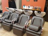 a row of chairs in a salon with a lot of hair dryers