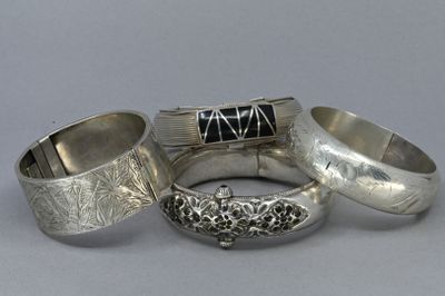 trois bagues en argent ornées de pierres noires, posées sur une table