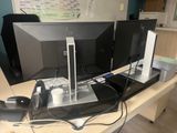 two computer monitors sitting on a desk next to each other