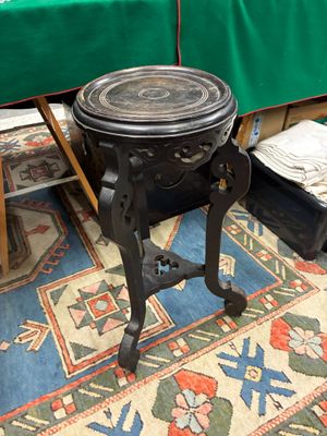 une petite table noire avec un plateau en bois, posée sur un tapis