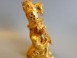 a gold figurine of a dog with a bell on it ' s neck