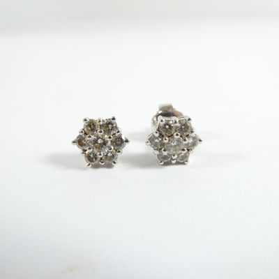 une paire de boucles d'oreilles en diamant sur une surface blanche