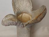 a white vase with a flower in it on a table