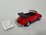 a red toy car with a black top on a white surface
