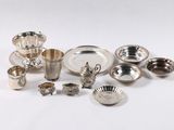 Plusieurs plats et tasses en argent sont disposés sur une surface blanche