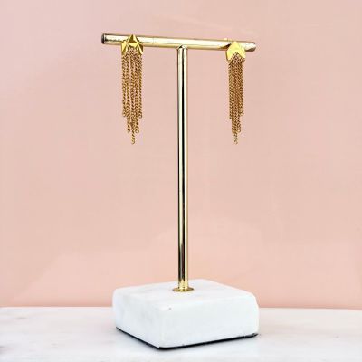 the gold star and chain earrings are on a marble stand