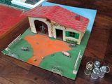 a model of a house on the floor next to a pair of scissors