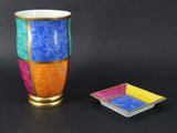 a colorful vase next to a square plate on a black surface
