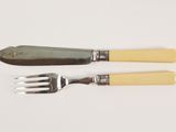 two forks and a knife on a white table