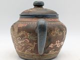 a brown and black teapot on a white surface