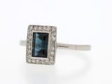 gros plan d'une bague avec une pierre bleue entourée de diamants blancs