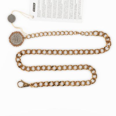 a gold chain with a coin on it next to a piece of paper
