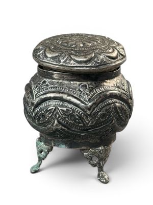 an ornate metal box with a lid on a white background