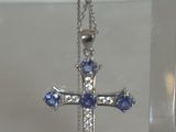 un pendentif en forme de croix bleue et blanche présenté dans un écrin transparent