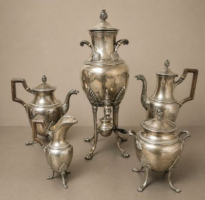 trois théières en argent et une cafetière sur une table