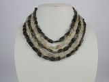 three strand necklace with black and white beads on a white mannequin