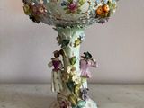 a white vase with flowers on it sitting on a table