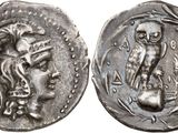 a silver coin with an image of a woman and an owl on it