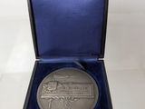 an image of a silver medal sitting in a blue case