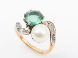a close up of a ring with a pearl and a green stone