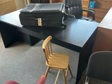a desk with a chair and a suitcase on top of it