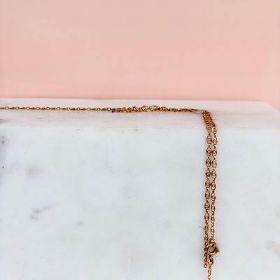 a close up of a gold necklace on a marble slab