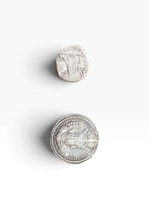 two silver coins sitting next to each other on a white surface