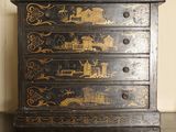 a black and gold chest of drawers with a clock on top