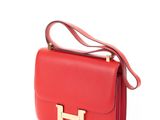 un sac à main en cuir rouge avec des finitions dorées sur fond blanc