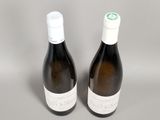 two bottles of white wine sitting next to each other on a table
