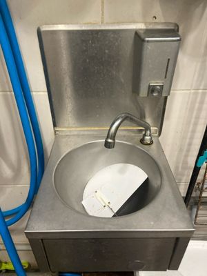 un lavabo dans des toilettes publiques équipé d'un tuyau bleu