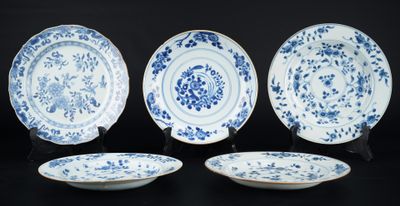 quatre assiettes bleues et blanches ornées de motifs floraux sur un fond noir