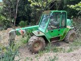 un tracteur vert garé sur la terre battue