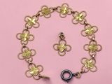 un gros plan d'un bracelet et d'une boucle d'oreille en or sur fond rose