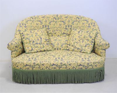 un canapé à motifs floraux jaunes et bleus, orné de franges vertes