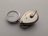 une montre de poche en argent et une horloge en argent posée sur une table