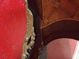 a red wall with a mirror on it and a chair in the corner