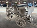 un cheval et une calèche dans une grange, avec une voiture en arrière-plan