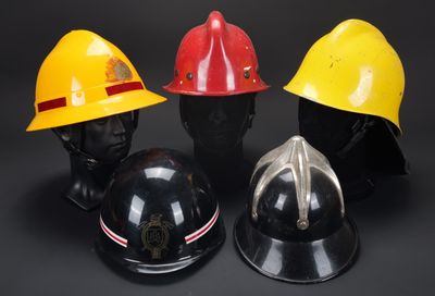 trois casques de pompier sont alignés sur une surface noire