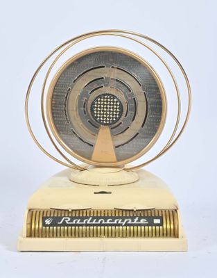 une image représentant une radio dorée et argentée posée sur une surface blanche