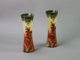 two vases with flowers painted on them on a table