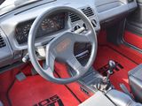 dashboard of a car with red carpeting and a steering wheel