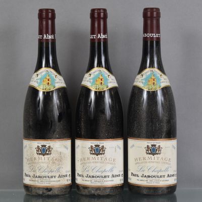 Trois bouteilles de vin sont alignées sur une table en verre