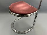 un gros plan d'une chaise dont l'assise est rouge, posée sur une surface blanche