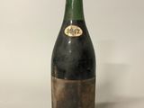 une vieille bouteille de vin posée sur une table blanche