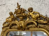 a mirror with a gold frame with cherensils on it