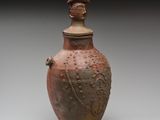 un vase marron surmonté d'un oiseau