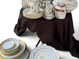 many plates and cups on a table with a black table cloth