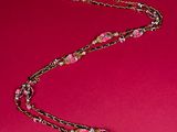 a close up of a pink necklace on a red background